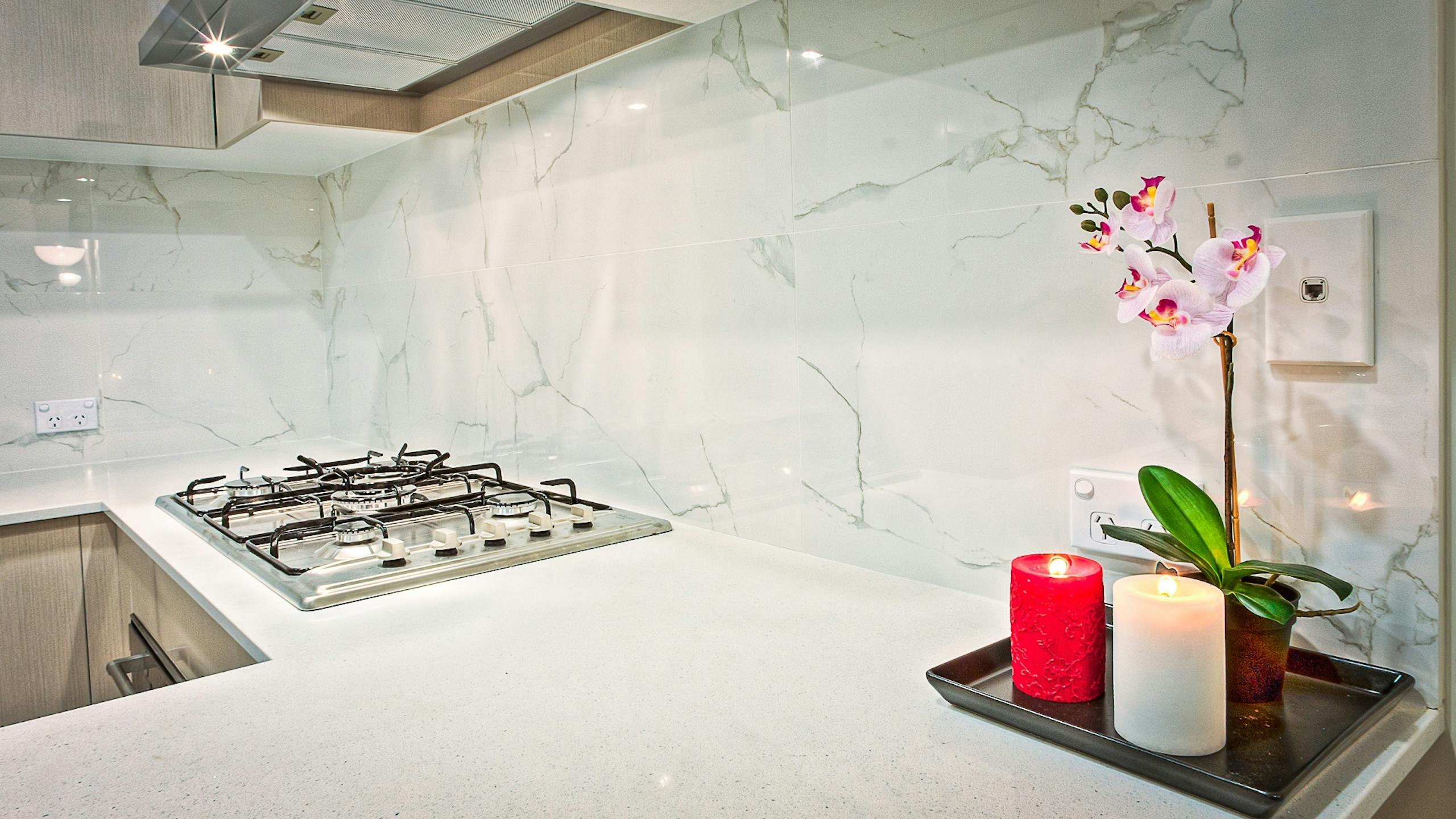 Stylish kitchen interior featuring decorative candles and orchids on a countertop.