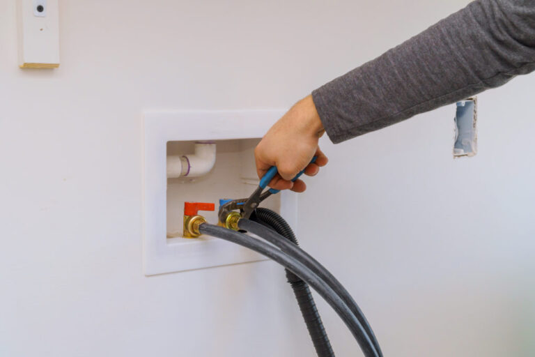 repair person tightening the hoses on the back of a washer