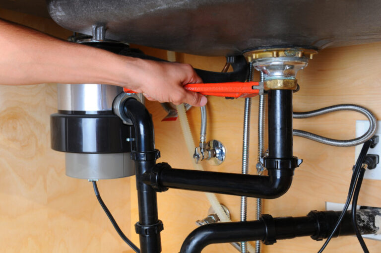 repairman working on a pipe under the sink