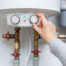 womans hand adjusts thermostat of hot water heater